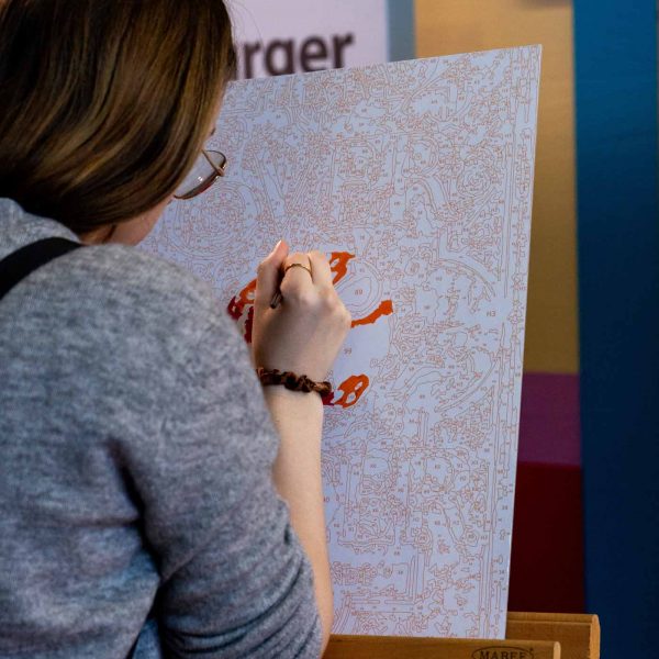 Eine Person, die auf dem Bookstock Festival Gelände auf einer Leinwand Malen nach Zahlen macht