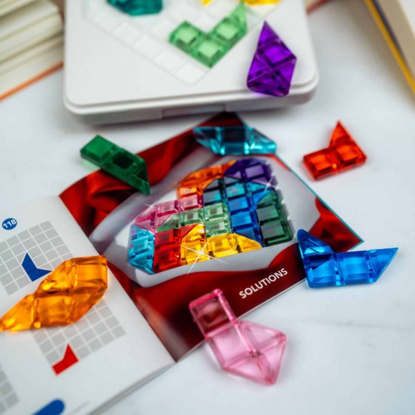 Das Spiel IQ Love, die Spielanleitung und die Spielsteine liegen auf einem weißen Untergrund