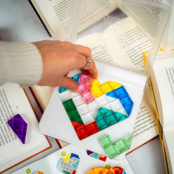 Das Spiel IQ Love auf einem offenen Buch und eine Person, die gerade Bausteine hinlegt