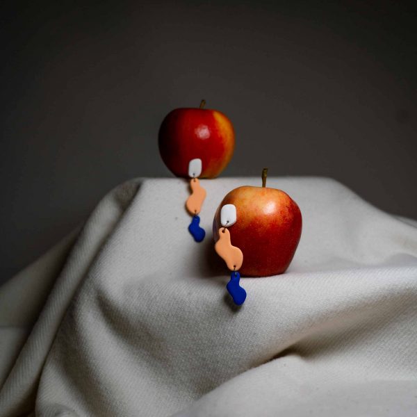 Zwei Aepfel in denen jeweils ein Ohrring steckt