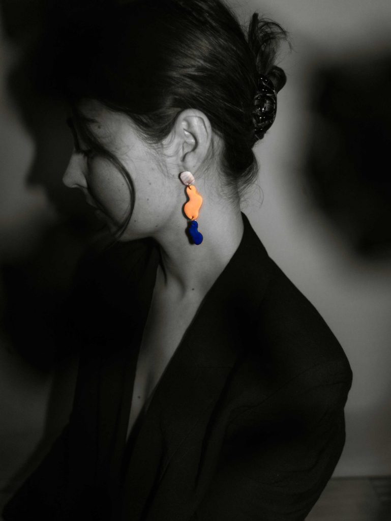 Frau mit Klammer im Haar in schwarz weiß und buntem Ohrring im linken Ohr