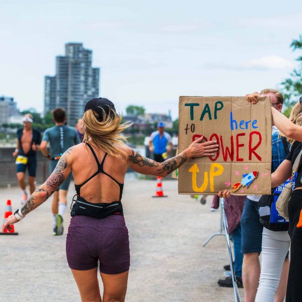 Frau beruehrt ein Plakat auf der Laufstrecke auf dem Tap here to Power up steht
